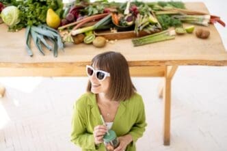 A woman sips lemonade with a variety of healthy foods visible in the background.