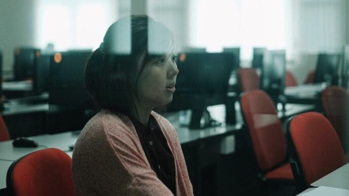 A woman sits at a desk in a classroom.