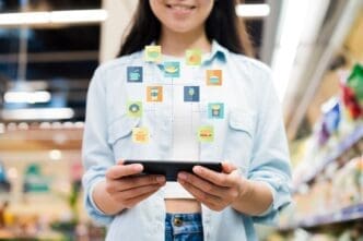 A woman uses a smartphone while standing in a grocery store.