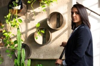 A young Arab investor in formal attire stands inside a modern greenhouse.