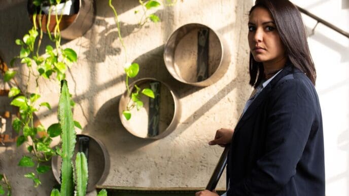 A young Arab investor in formal attire stands inside a modern greenhouse.