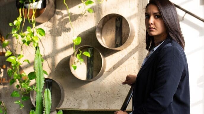 A young Arab investor in formal attire stands inside a modern greenhouse.