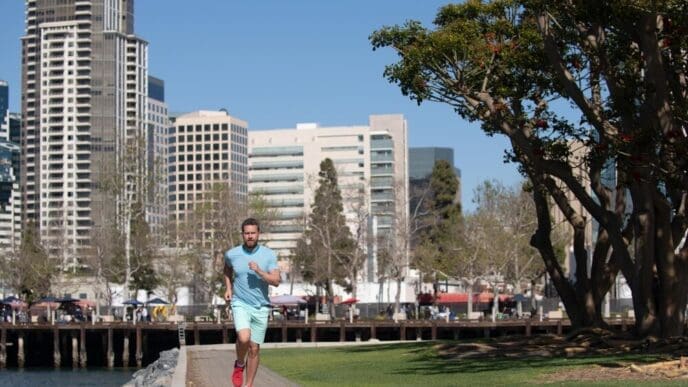 Full-length shot of a young, athletic man running through a park in San Diego.