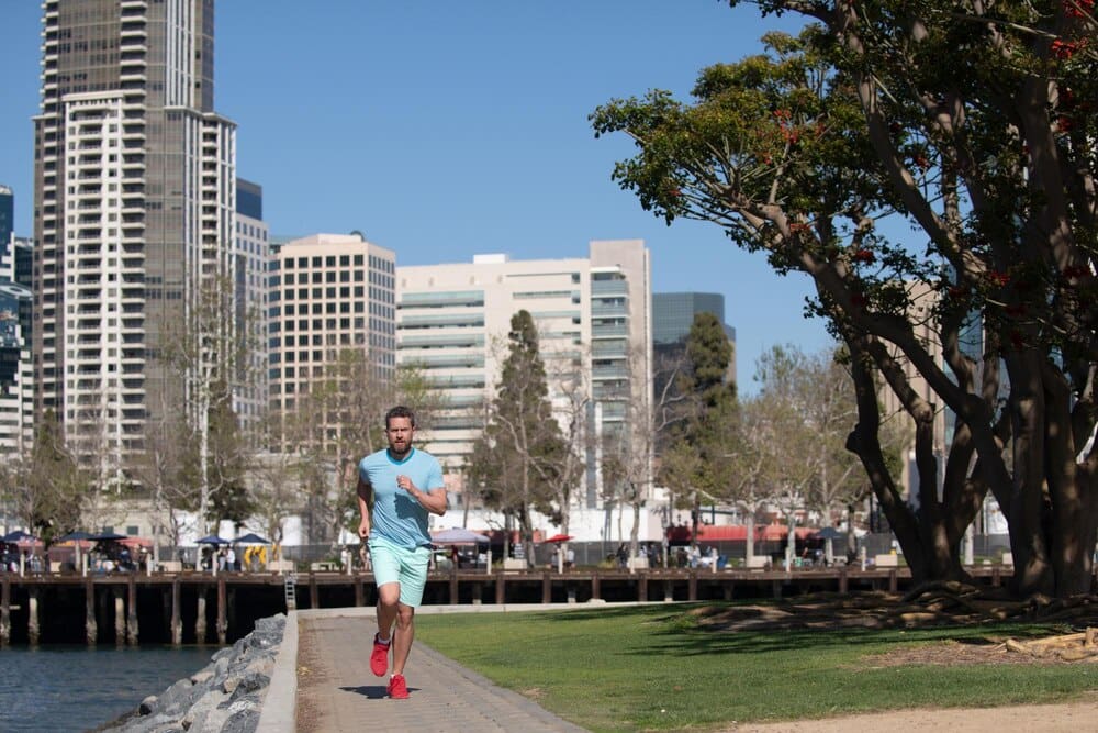 Full-length shot of a young, athletic man running through a park in San Diego.