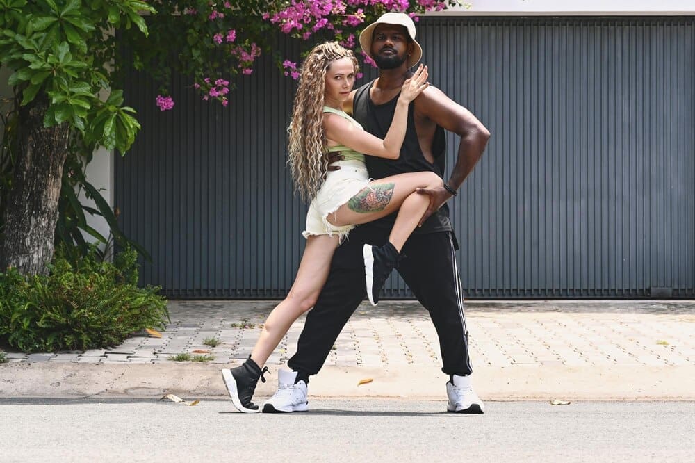 A young couple dances joyfully in the middle of a street.