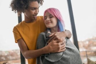 A young couple smiles while spending time together indoors.