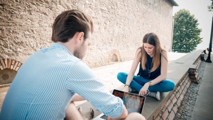 Young couple using a smartphone, tablet, and notebook simultaneously.