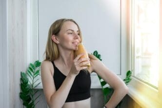 Young woman with long hair sits on a windowsill, gazing away from the camera.