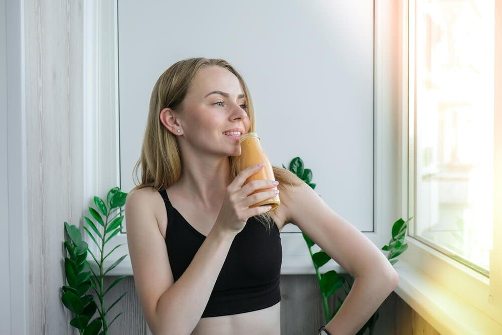 Young woman with long hair sits on a windowsill, gazing away from the camera.