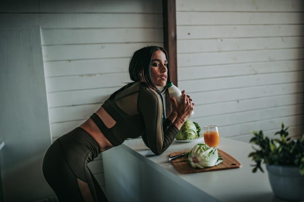 A young woman sits at a table against a wall.