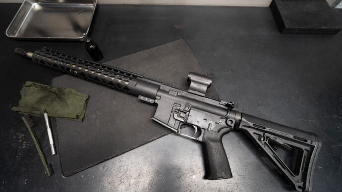 AR-15 rifle with red dot sight on a gunsmith's workbench