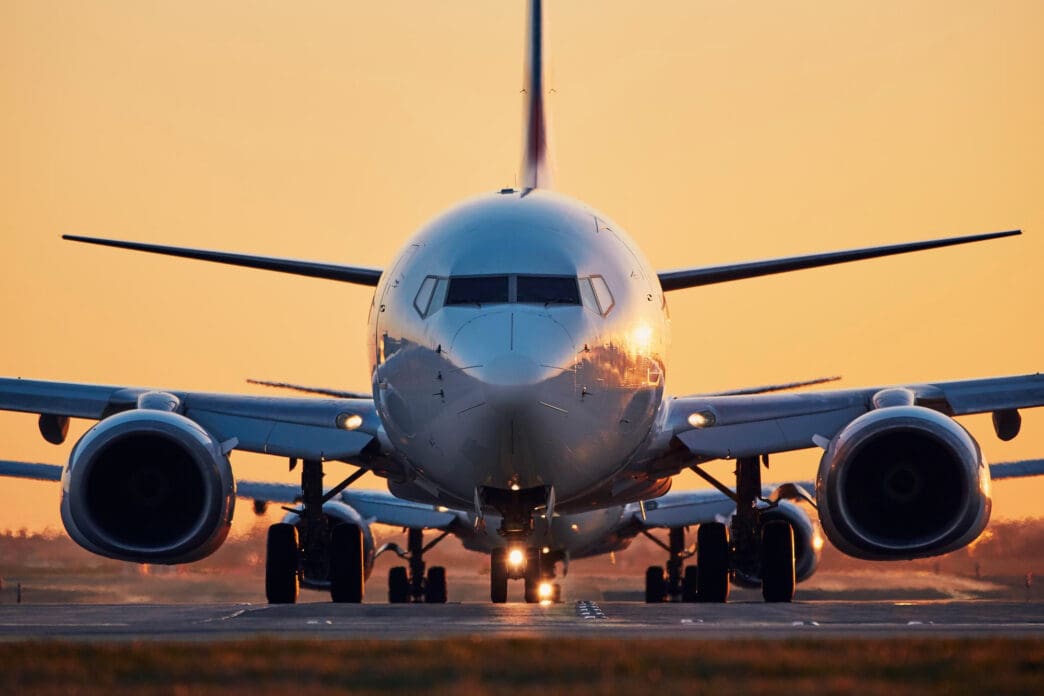 Airplane on runway at sunset with warm orange sky