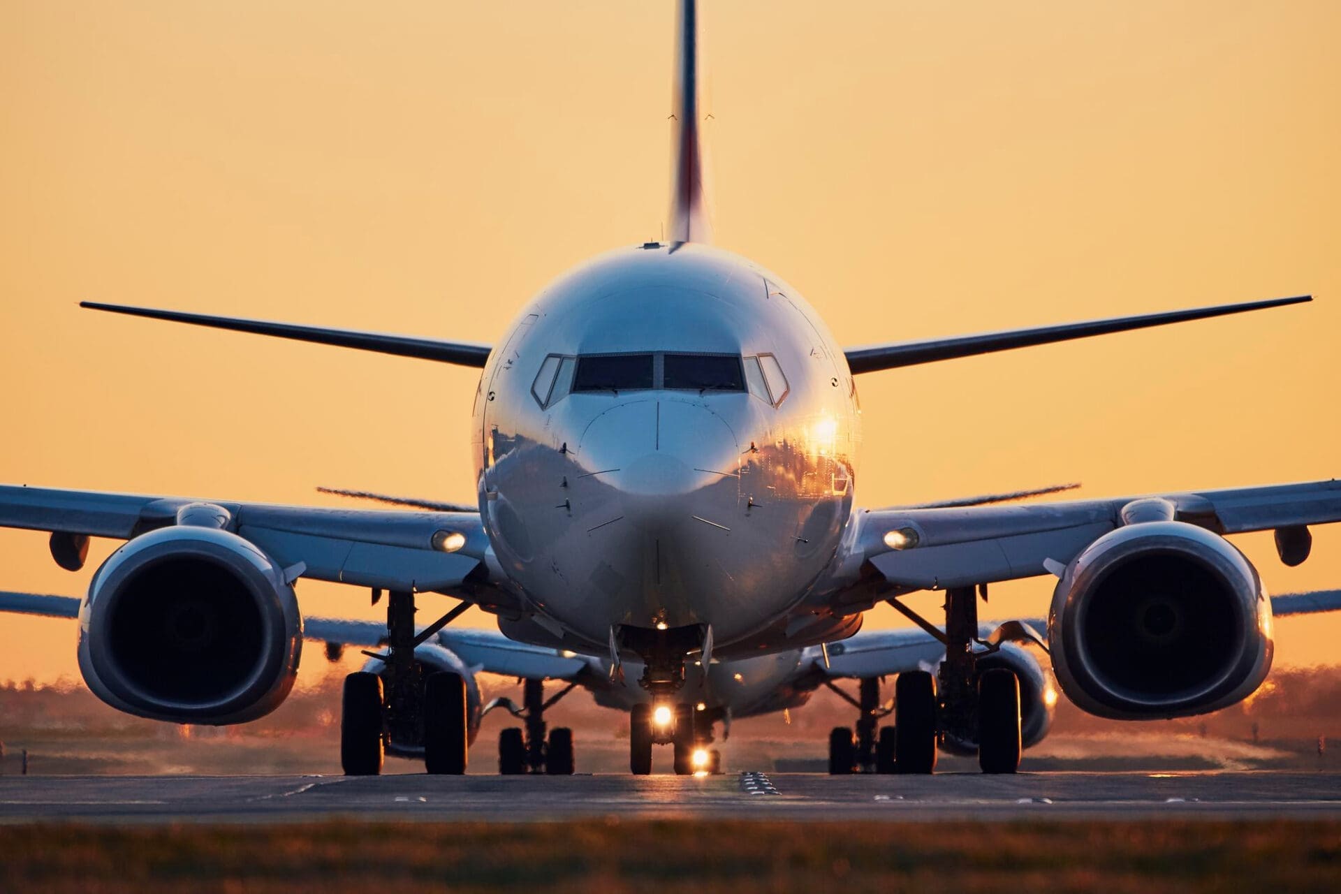 Airplane on runway at sunset with warm orange sky