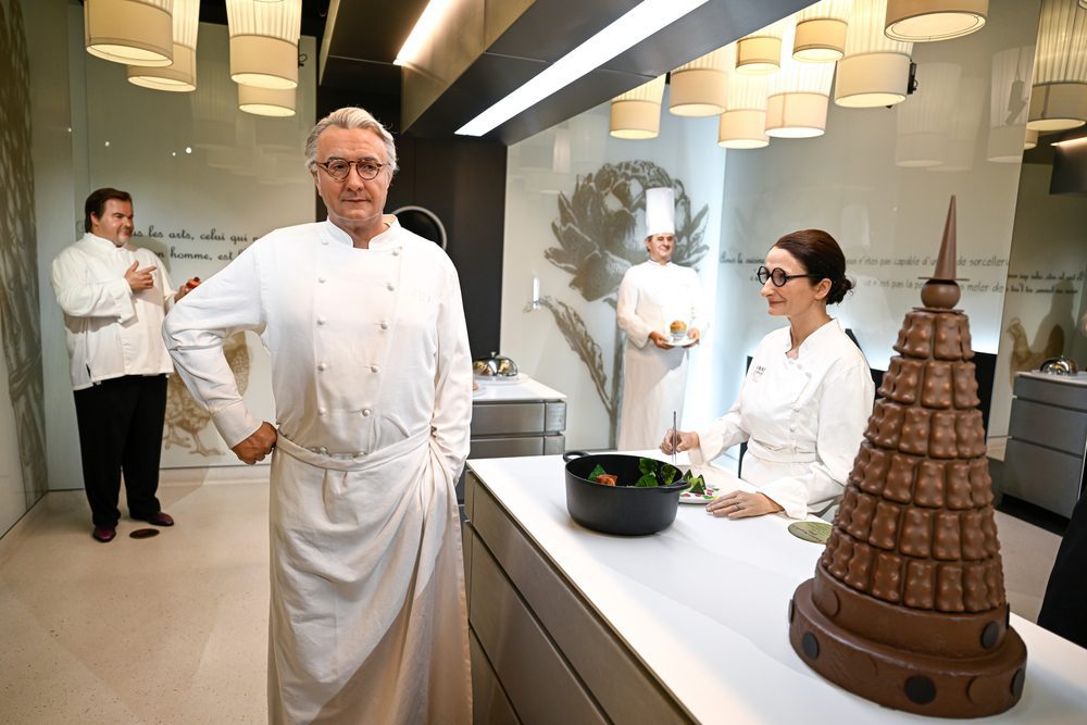 The wax statue of French chef Alain Ducasse stands in a museum kitchen exhibit