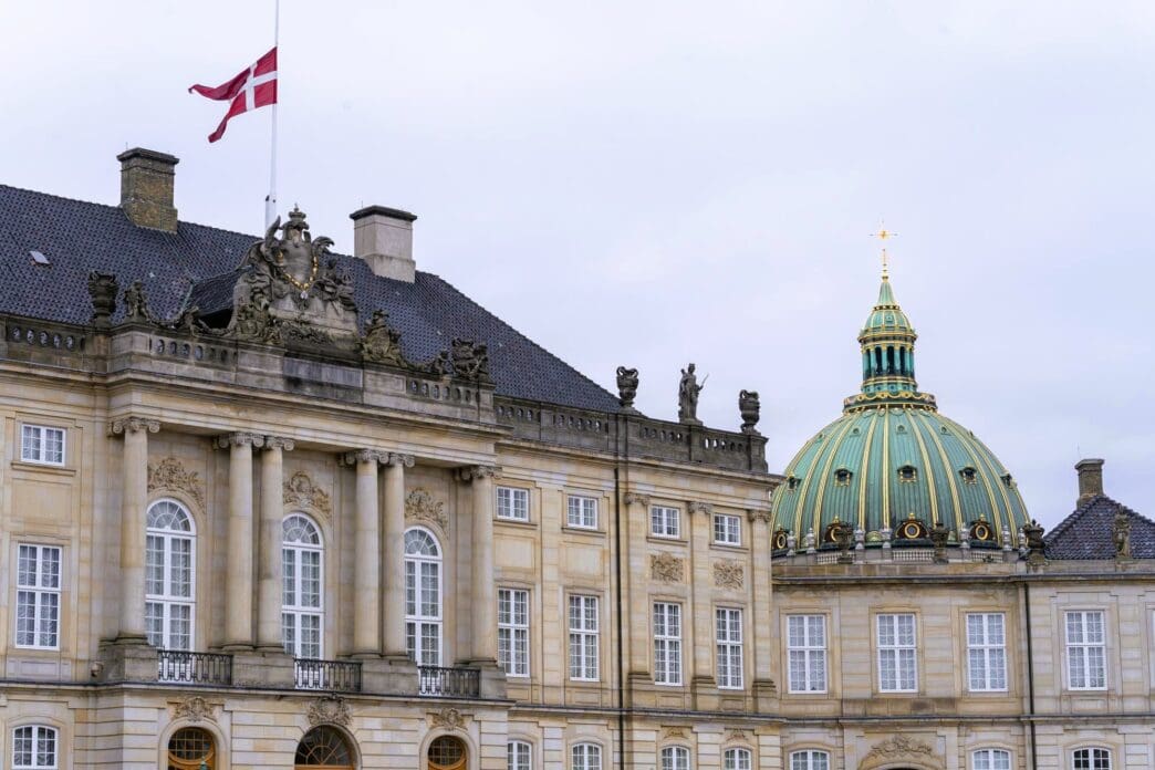 The Danish flag flies high above Amalienborg Palace's ornate facade.