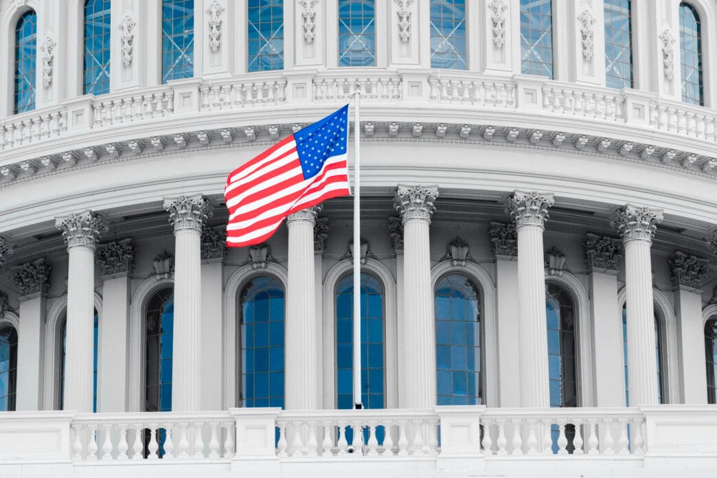 American flag waving in front of the U.S. Capitol building