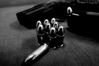 Close-up of bullets and a handgun on a dark textured surface