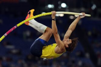 Armand "Mondo" Duplantis of Sweden in mid-air during a pole vault event, holding a yellow pole
