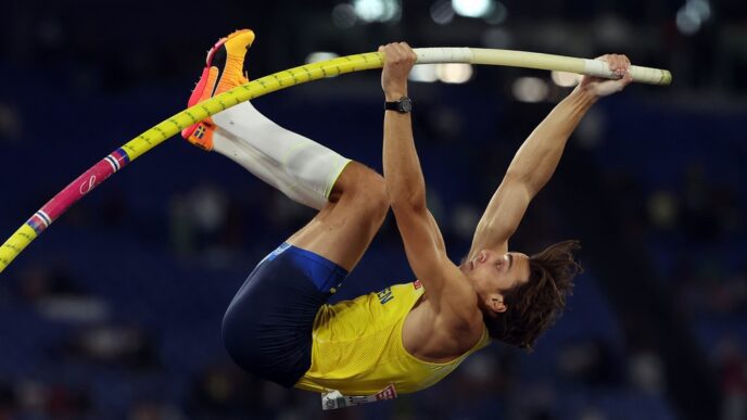 Armand "Mondo" Duplantis of Sweden in mid-air during a pole vault event, holding a yellow pole