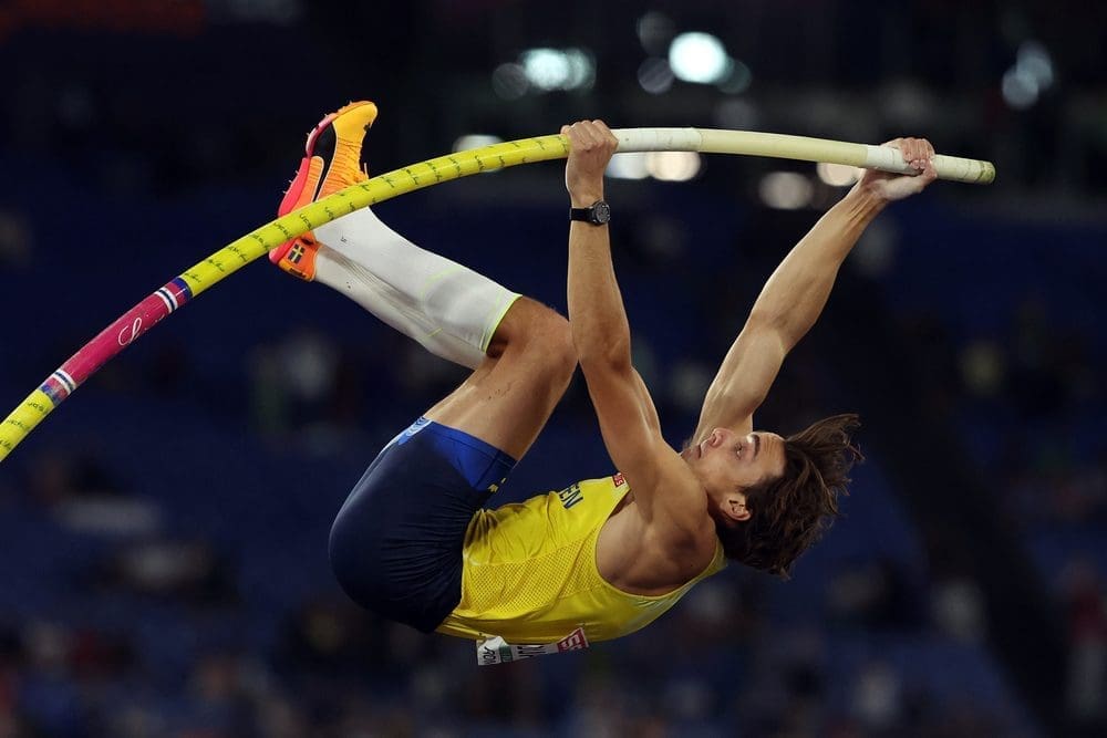 Armand "Mondo" Duplantis of Sweden in mid-air during a pole vault event, holding a yellow pole