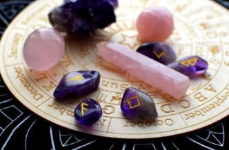 Amethyst and rose quartz crystals arranged on a wooden disc with astrological symbols and months