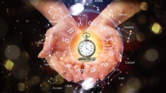 Hands hold a glowing pocket watch, encircled by the twelve symbols and constellations of the zodiac