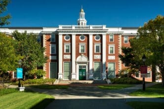 The Baker Library at Harvard Business School, a large red brick building with white columns under a clear blue sky