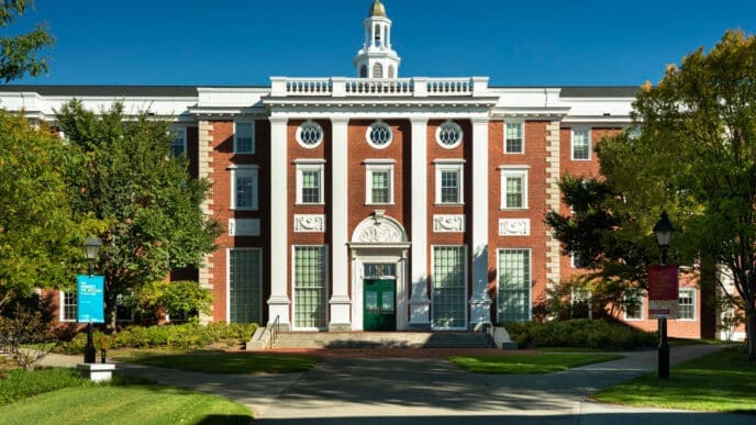 The Baker Library at Harvard Business School, a large red brick building with white columns under a clear blue sky