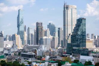 The dense, modern skyline of Bangkok, Thailand, with the "pixelated" MahaNakhon building on the left