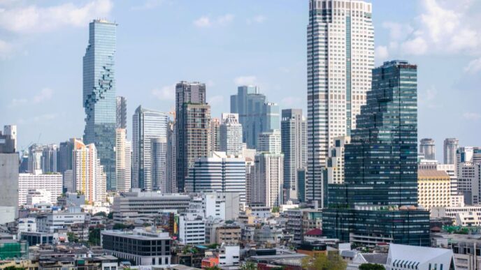 The dense, modern skyline of Bangkok, Thailand, with the "pixelated" MahaNakhon building on the left