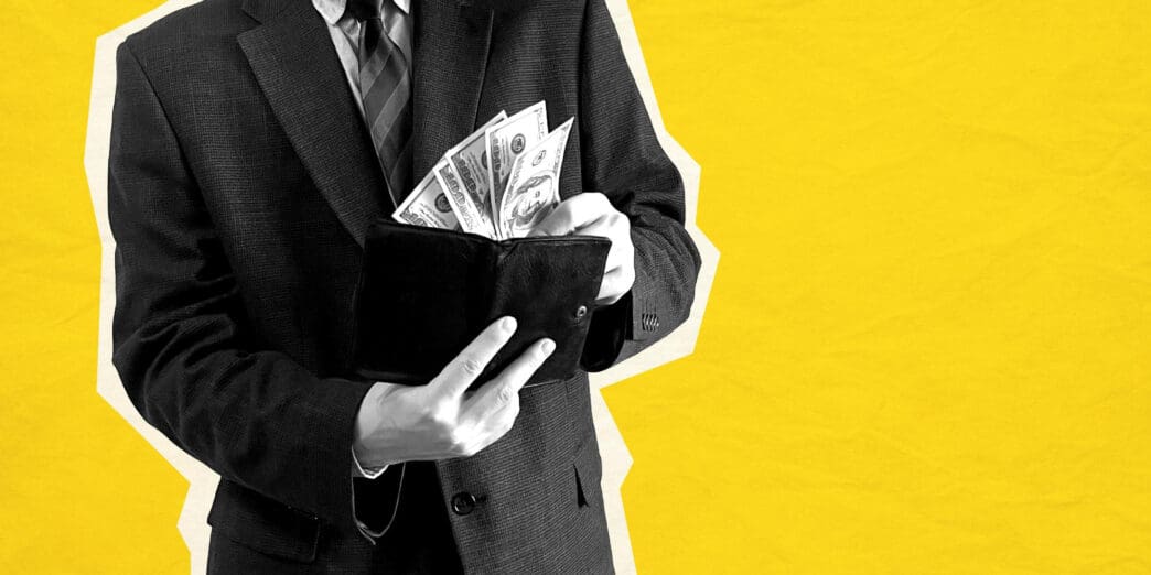 Man in suit putting US dollars into a wallet