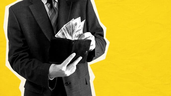 Man in suit putting US dollars into a wallet