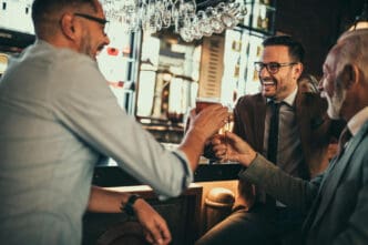Three men toasting with beer glasses at a bar