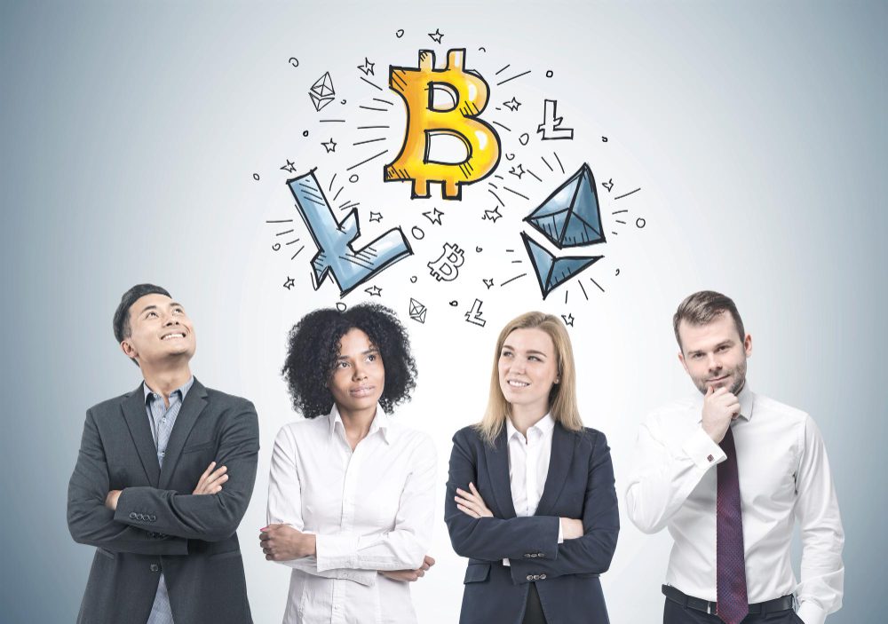 Four diverse businesspeople looking up at a drawing of a Bitcoin and other cryptocurrencies