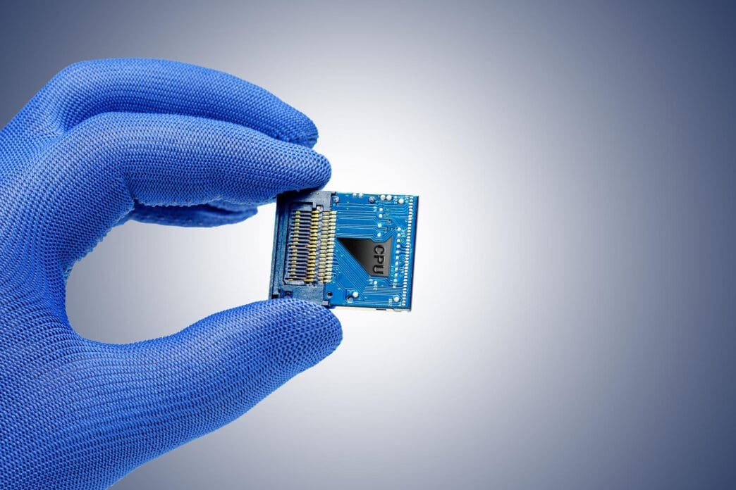 Hand in blue glove holding a CPU chip