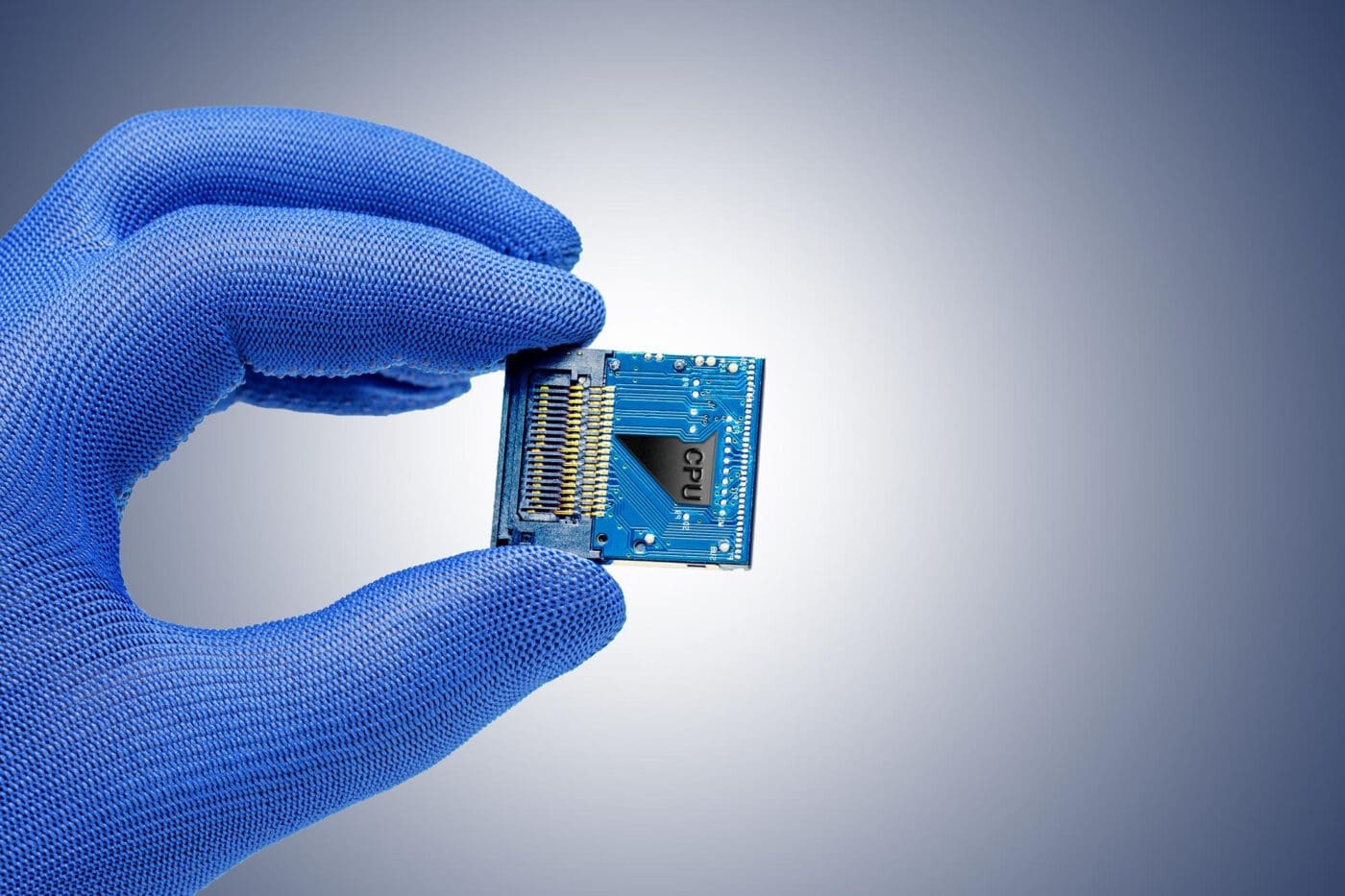 Hand in blue glove holding a CPU chip