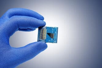 Hand in blue glove holding a CPU chip