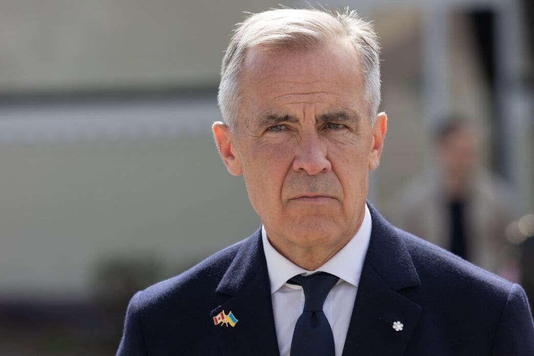 A close-up of a man in a suit with Canadian and Ukrainian flags on his lapel.