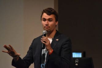 Charlie Kirk gestures while speaking into a microphone at Texas State University
