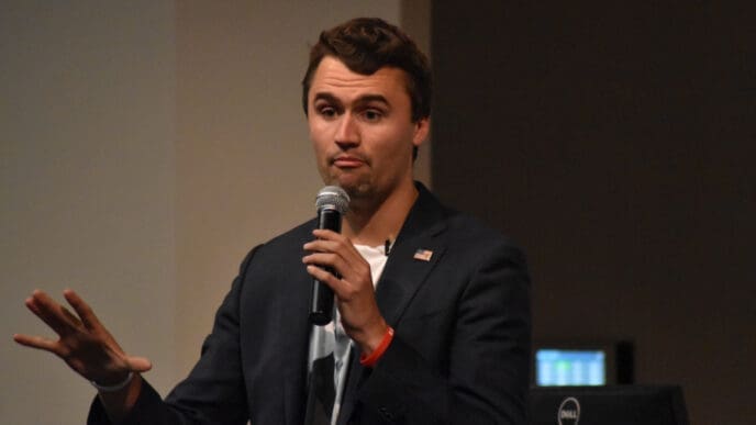 Charlie Kirk gestures while speaking into a microphone at Texas State University