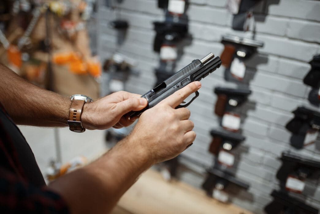 A man holds a handgun while shopping in a gun store
