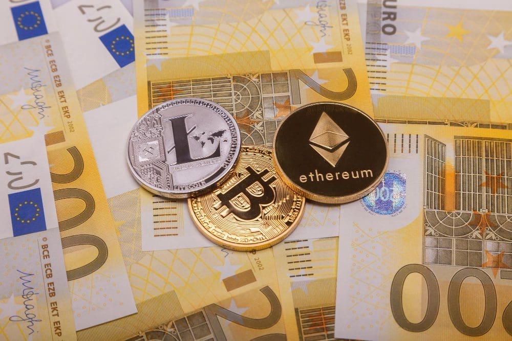 Three different cryptocurrency coins, Bitcoin, Ethereum, and Litecoin, on top of Euro banknotes