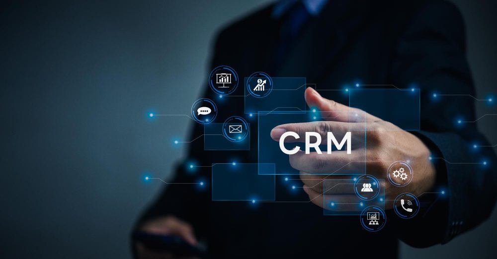 A person in a suit points to the glowing letters "CRM" surrounded by digital icons