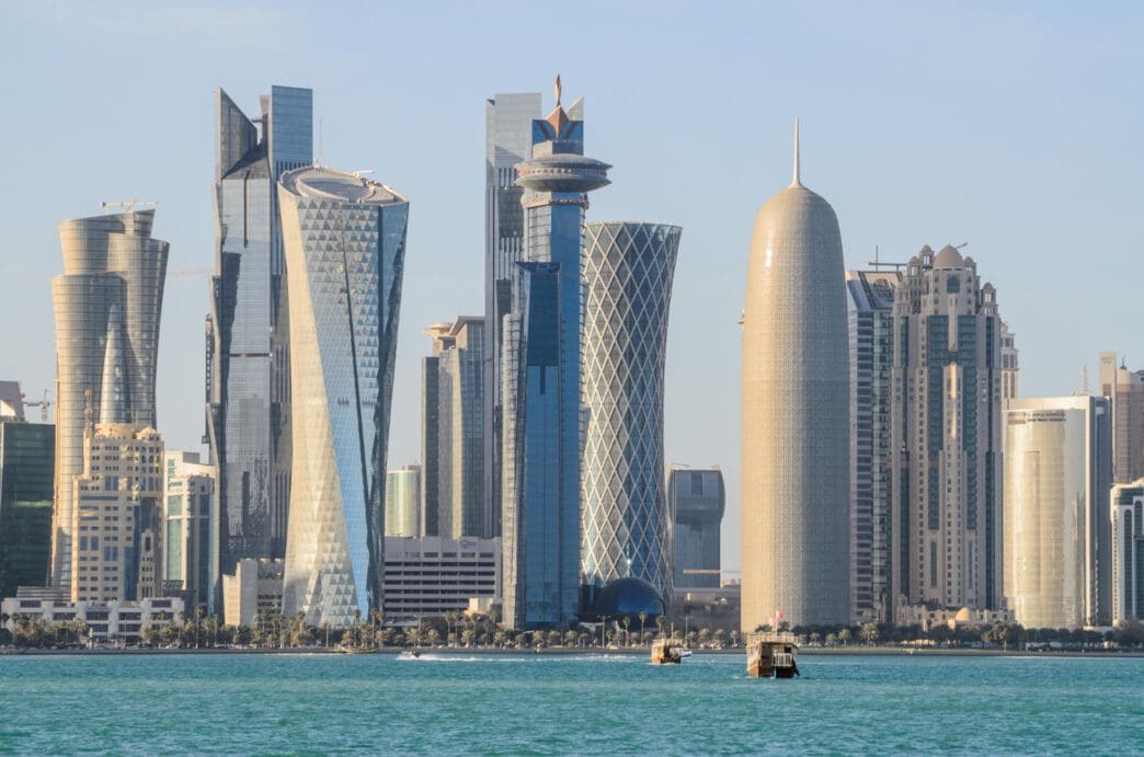 The futuristic skyline of Doha, Qatar, with a variety of unique skyscrapers along a waterfront, on a clear day