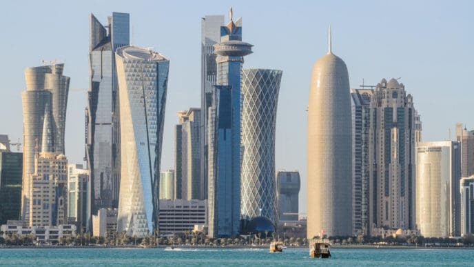 The futuristic skyline of Doha, Qatar, with a variety of unique skyscrapers along a waterfront, on a clear day