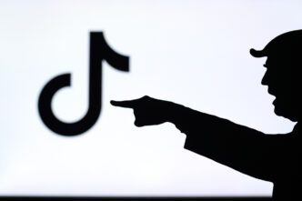 The silhouette of a person pointing a finger at a blurred TikTok logo on a screen