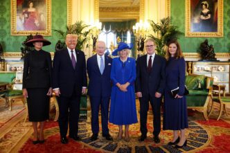 World leaders and their spouses stand for a group photo in a lavish room in Windsor Castle