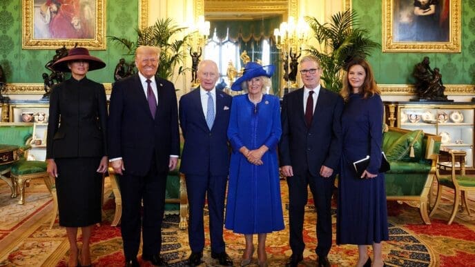 World leaders and their spouses stand for a group photo in a lavish room in Windsor Castle