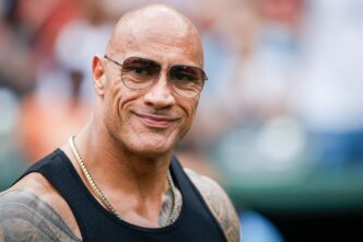 Dwayne "The Rock" Johnson smiling and wearing sunglasses at an outdoor event