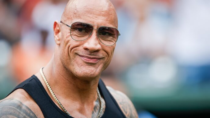 Dwayne "The Rock" Johnson smiling and wearing sunglasses at an outdoor event